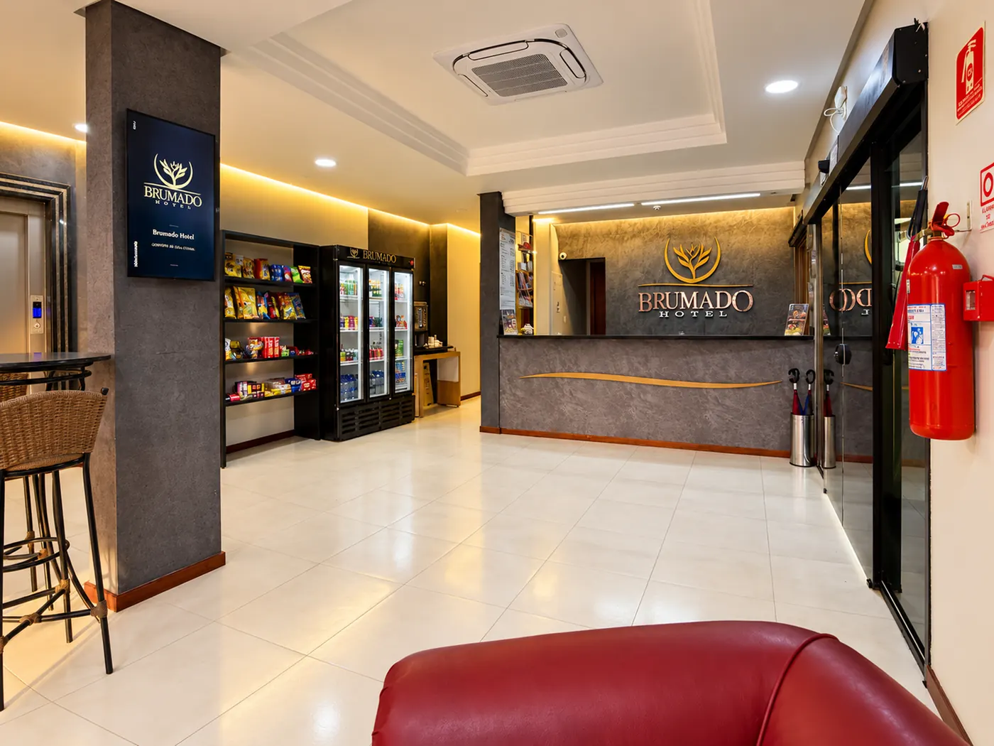 Recepção do Brumado Hotel com o logotipo na parede e área de conveniência